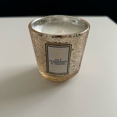 a close up of a candle on a table with a white surface in the background