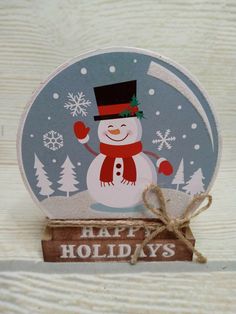 a snow globe sitting on top of a wooden table next to a sign that says happy holidays