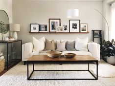 a living room filled with furniture and framed pictures on the wall above a coffee table