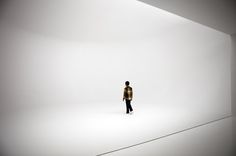 a man standing in the middle of a white room with his back to the camera