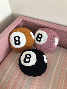 three balls sitting on top of a bed next to each other in a pink room