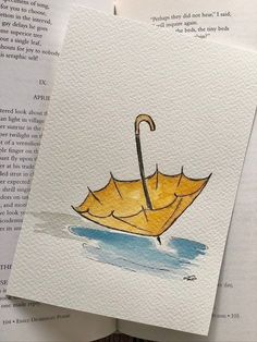 an open book with watercolor and ink drawings of an umbrella on top of it