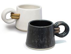 two coffee mugs with handles are sitting next to each other on a white surface