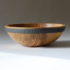 a wooden bowl sitting on top of a white table next to a black and gray stripe