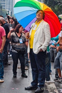 a man holding an umbrella in the middle of a street with people standing around him