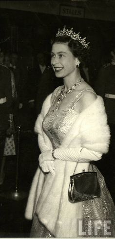 an old black and white photo of a woman wearing a tiara with her hands in her pockets