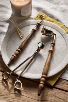 a white plate topped with different types of kitchen utensils next to a candle