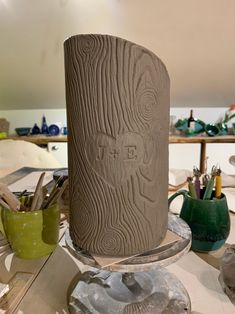 a vase sitting on top of a wooden table next to other pottery and art supplies