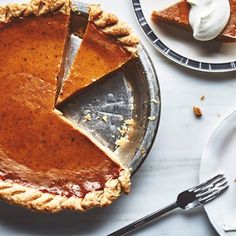 there is a pie on the table next to plates and utensils, with one slice missing