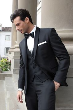 a man in a tuxedo is standing outside