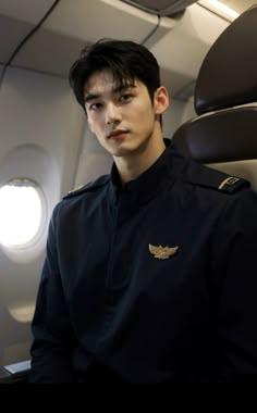 a young man in uniform sitting on an airplane looking at the camera with his eyes closed