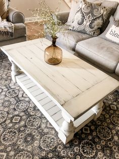 a white coffee table sitting on top of a rug in a living room next to a couch