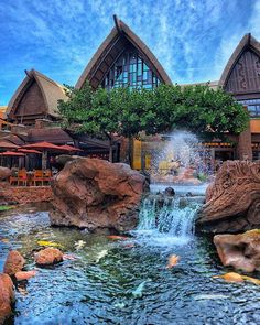 a large waterfall in the middle of a pond surrounded by rocks and water features an elaborate building