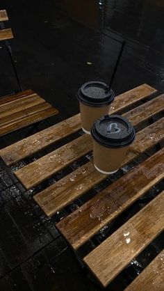 two coffee cups sitting on top of wooden benches