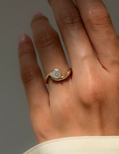 a woman's hand with a diamond ring on top of her left hand,