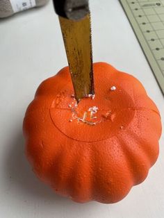 an orange pumpkin being cut with a large knife