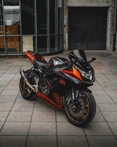 an orange and black motorcycle parked in front of a building