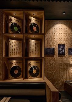 a room with wooden shelves filled with vinyl records on the wall and lights above them