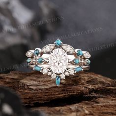 a diamond and turquoise stone ring on top of a tree branch with rocks in the background