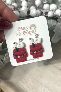 a pair of cat and dog earrings sitting on top of a white table next to a christmas tree