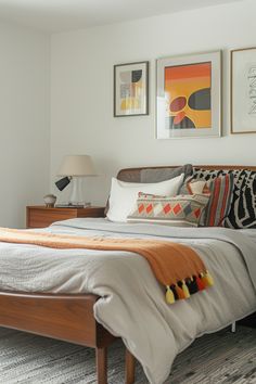 a bed sitting in a bedroom next to two framed pictures on the wall above it