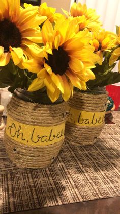 three sunflowers are sitting in two vases on a table with twine wrapped around them