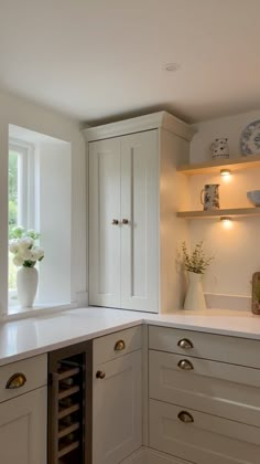 a kitchen with white cupboards and drawers next to a wine glass rack in the corner