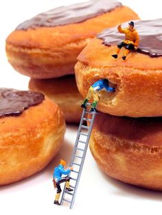 miniature people are working on giant donuts