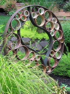 a circular metal sculpture sitting in the middle of a garden