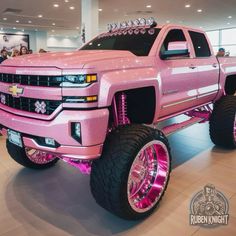 a pink truck with chrome rims is on display