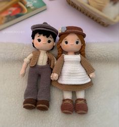 two crocheted dolls sitting next to each other on a blanket with books in the background