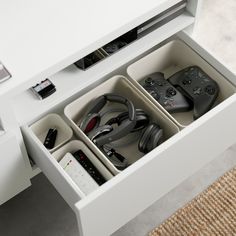 an entertainment center with remotes and video game controllers in it's drawer space