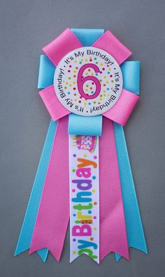 a pink and blue ribbon with the number six on it's side that says happy 6th birthday