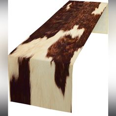 a cow print table runner on top of a white surface with black and brown spots