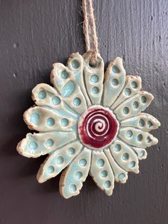 a ceramic ornament hanging on a wall with a red and white swirl in the center