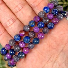 a hand holding several beads in different colors on it's palm, with succulents nearby