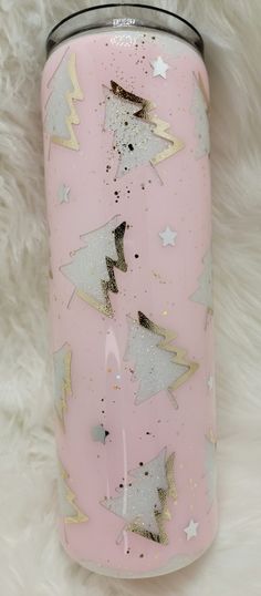 a pink can with gold and silver stars on it sitting on a white furry surface