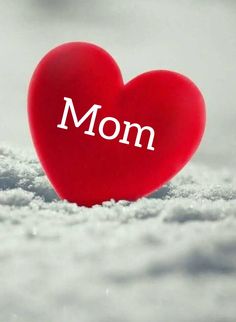 a red heart with the word mom written on it in white letters next to snow