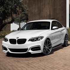 a white bmw car parked in front of a building