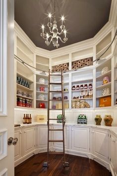 a ladder in the corner of a room with white cabinets and shelves filled with bottles