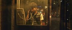 a man talking on a cell phone while standing in front of a window at night