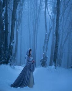 a woman in a long dress standing in the snow