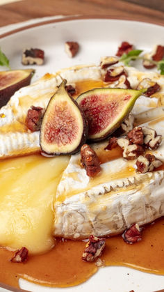 a white plate topped with cheese and figs covered in sauce on top of a wooden table