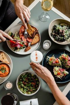 people are sitting at a table with plates of food