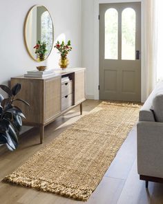 a living room with a couch, mirror and plant on the wall next to it