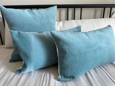 two blue pillows sitting on top of a bed