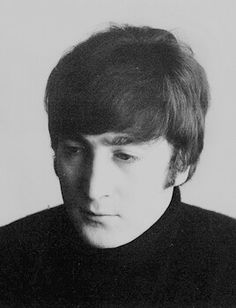 a black and white photo of a young man wearing a turtle neck sweater looking at the camera