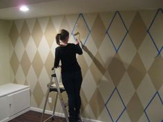 a woman standing on a ladder painting a wall