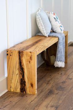 a wooden bench sitting on top of a hard wood floor next to a white wall