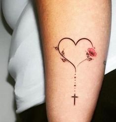 a woman's arm with a cross on it and a heart shaped tattoo design